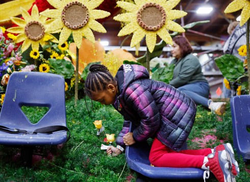 A girl adds flowers to a colorful scene decorated with big sunflowers.